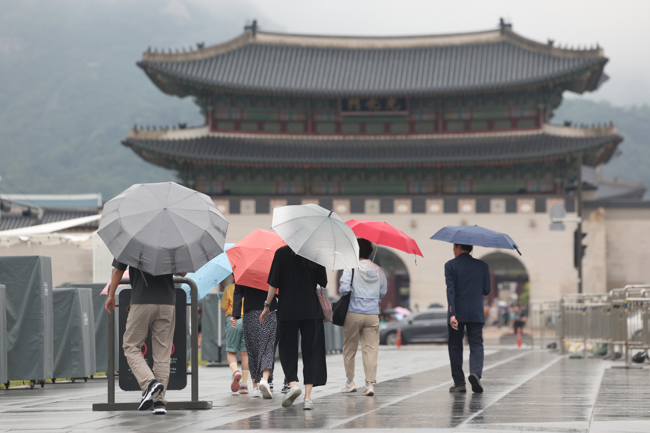 Pedestrians walk with umbrellas near Gwanghwamun Square in Seoul on Sunday. (Yonhap)