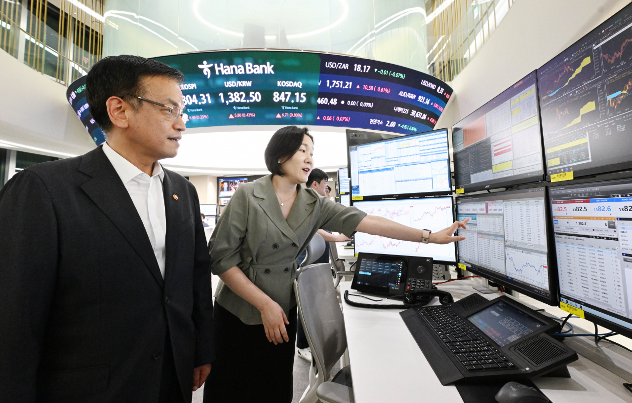 Finance Minister Choi Sang-mok is briefed by a KEB Hana Bank official at the foreign exchange dealing room at the bank's headquarters in Seoul, Monday. (Yonhap)