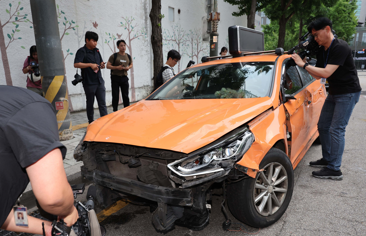 Reporters and officials examine the taxi that crashed into the National Medical Center in Jung-gu, Seoul, Wednesday. (Yonhap)