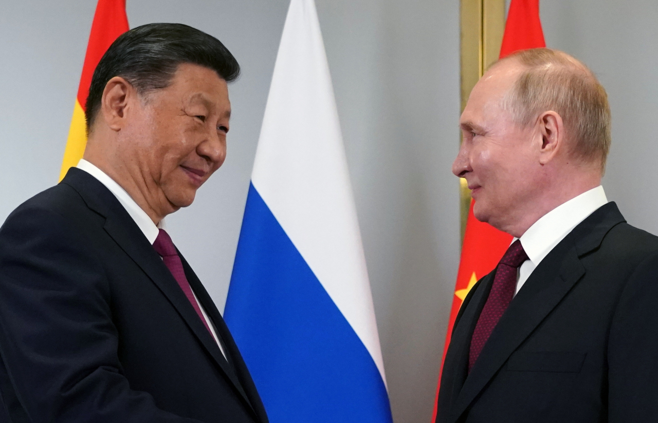 Russian President Vladimir Putin (right) and Chinese President Xi Jinping shake hands as they pose for photos during their meeting on the sidelines of the Shanghai Cooperation Organization summit in Astana, Kazakhstan, Wednesday. (Kremlin Pool via EPA)
