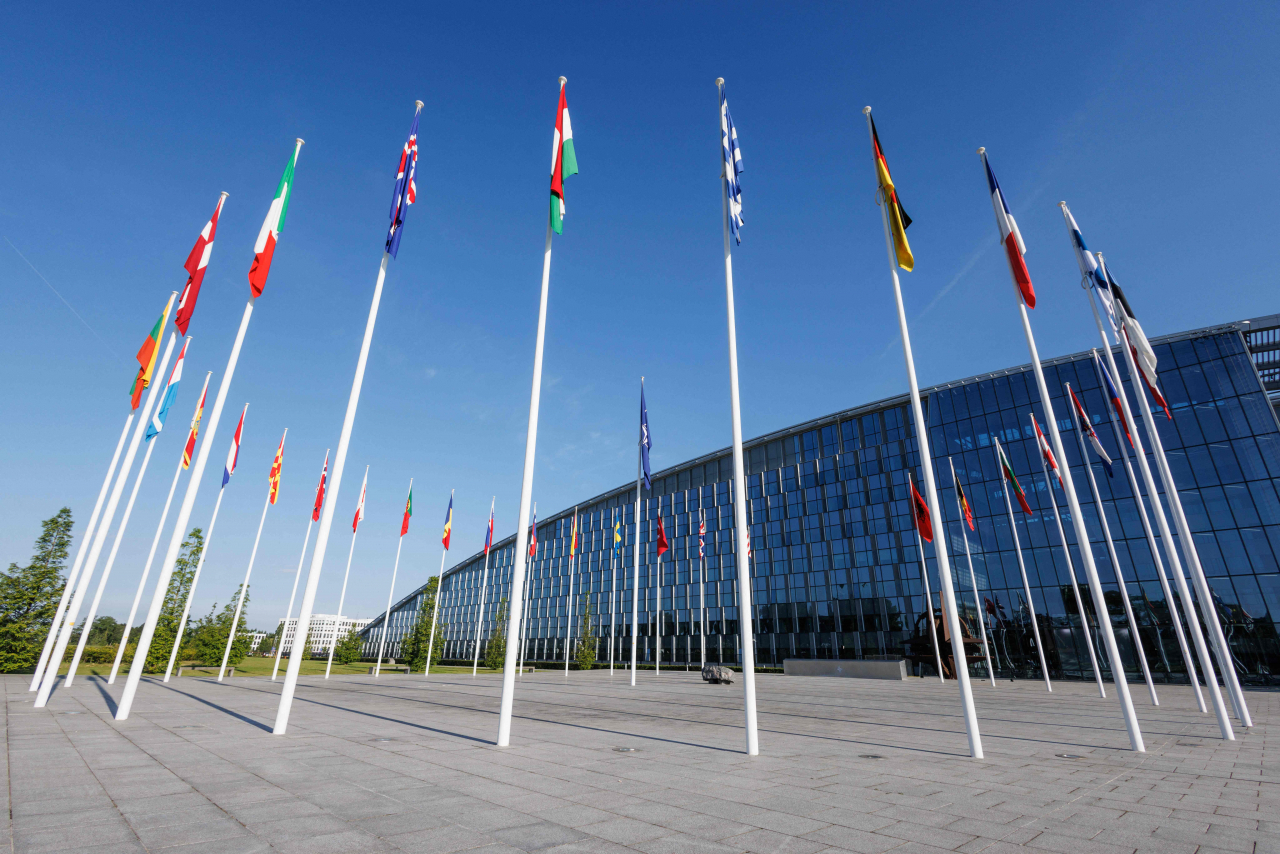 Flagpoles bearing national flags of NATO members adorn the entrance of NATO Headquarters in Brussels on June 13. (AFP-Yonhap)