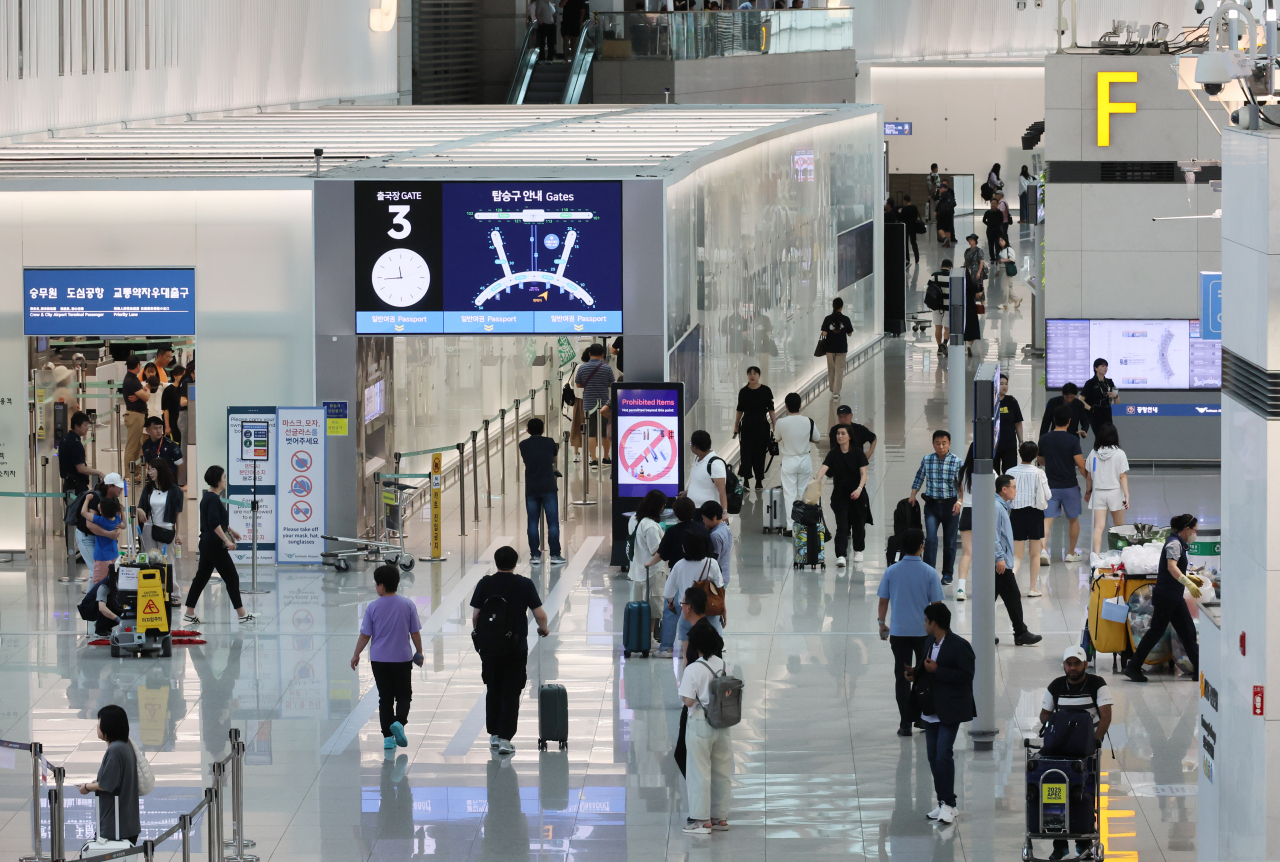 People walk through Terminal 1 at Incheon International Airport on Sunday. (Yonhap)