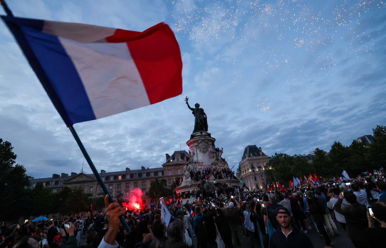 A participant waves a French national tricolor during an election night rally following the first results of the second round of France's legislative election at Place de la Republique in Paris on Sunday. (AFP-Yonhap)