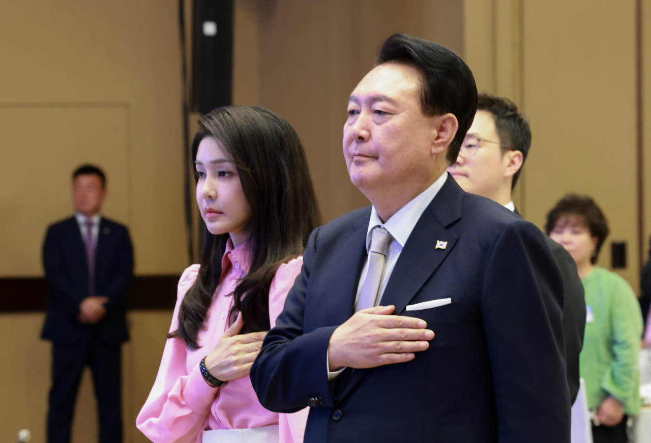 President Yoon Suk Yeol (right) and first lady Kim Keon Hee salute the national flag as they met overseas Koreans in Honolulu, Hawaii on Monday. (Yonhap)