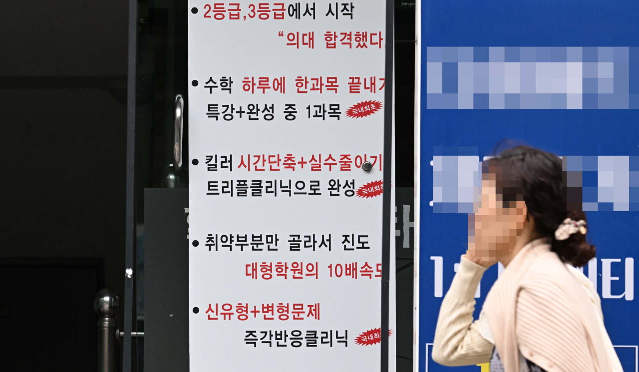 A woman walks past hagwon advertisements in this 2023 file photo. (Lee Sang-sub/The Korea Herald)