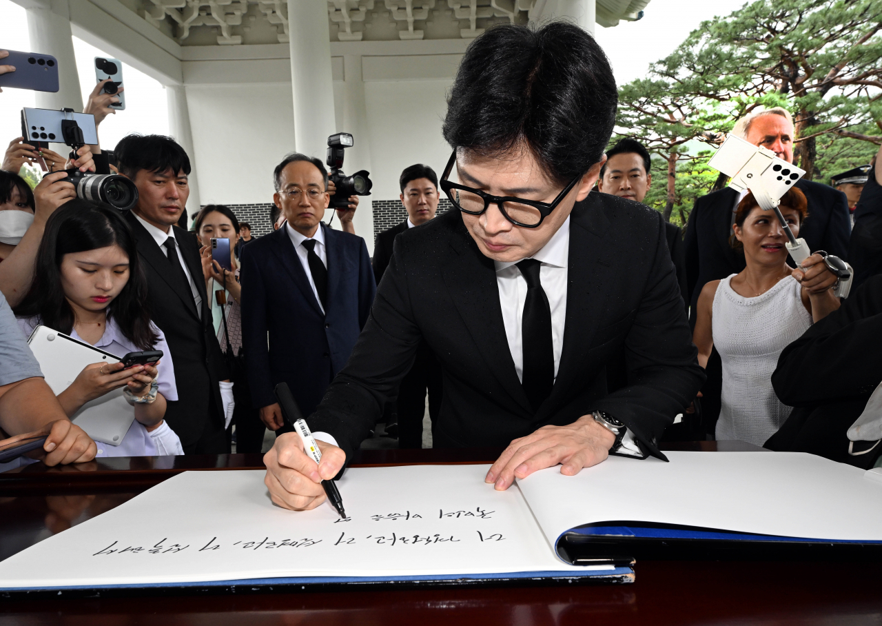 People Power Party Chair Han Dong-hoon writes a message on a guestbook as he visited the Seoul National Cemetery in Seoul on Wednesday. (Yonhap)