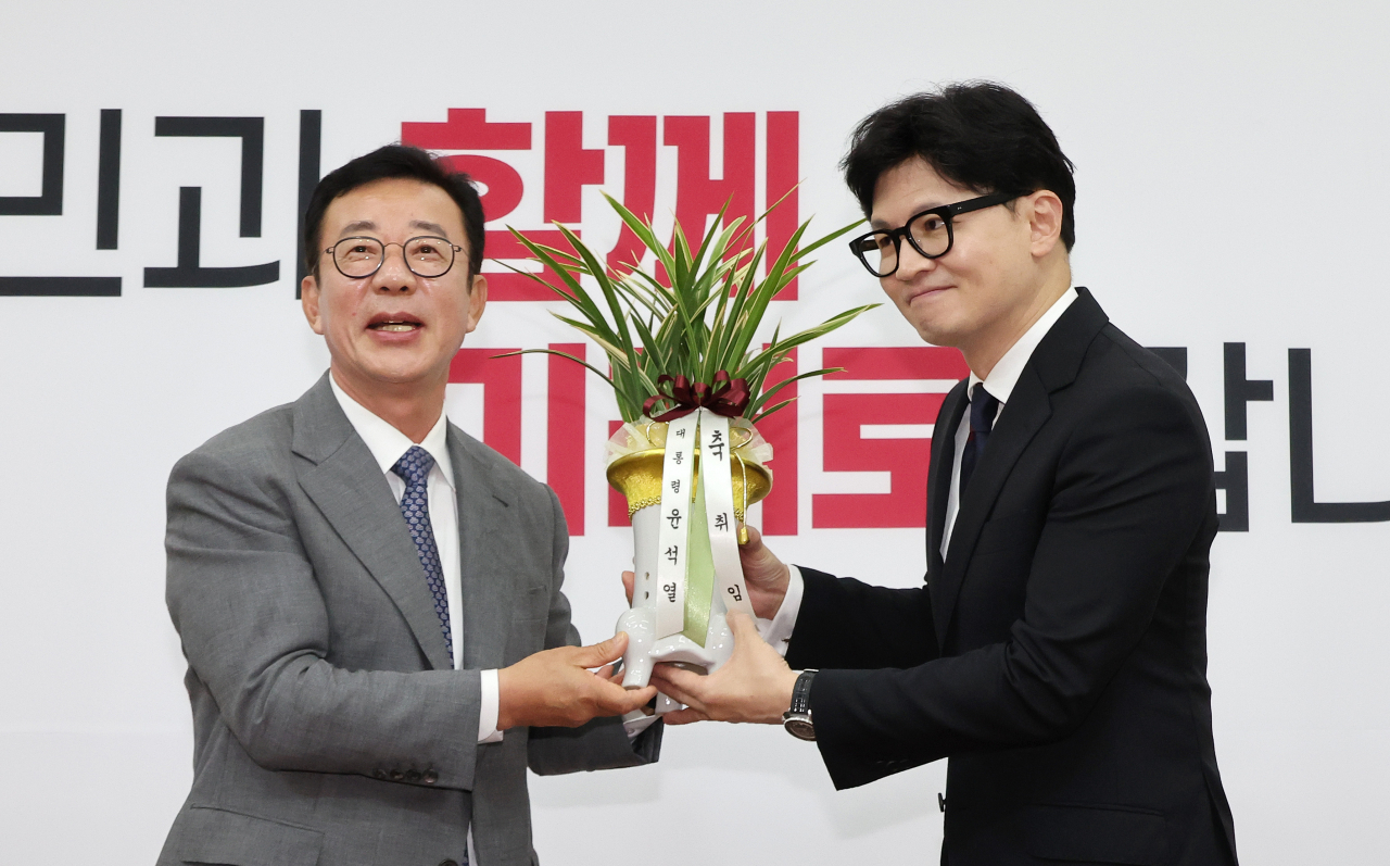 People Power Party Chair Han Dong-hoon (right) holds a Korean orchid gifted by Hong Chul-ho (left), senior presidential secretary for political affairs, as Han greeted Hong in the National Assembly in Seoul Wednesday. (Yonhap)