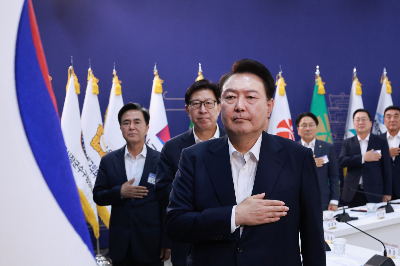 President Yoon Suk Yeol (third from left) salutes to the national flag as he presided over a meeting with heads of local autonomous governments in Hongseong-gun, South Chungcheong Province, Thursday. (Yonhap)