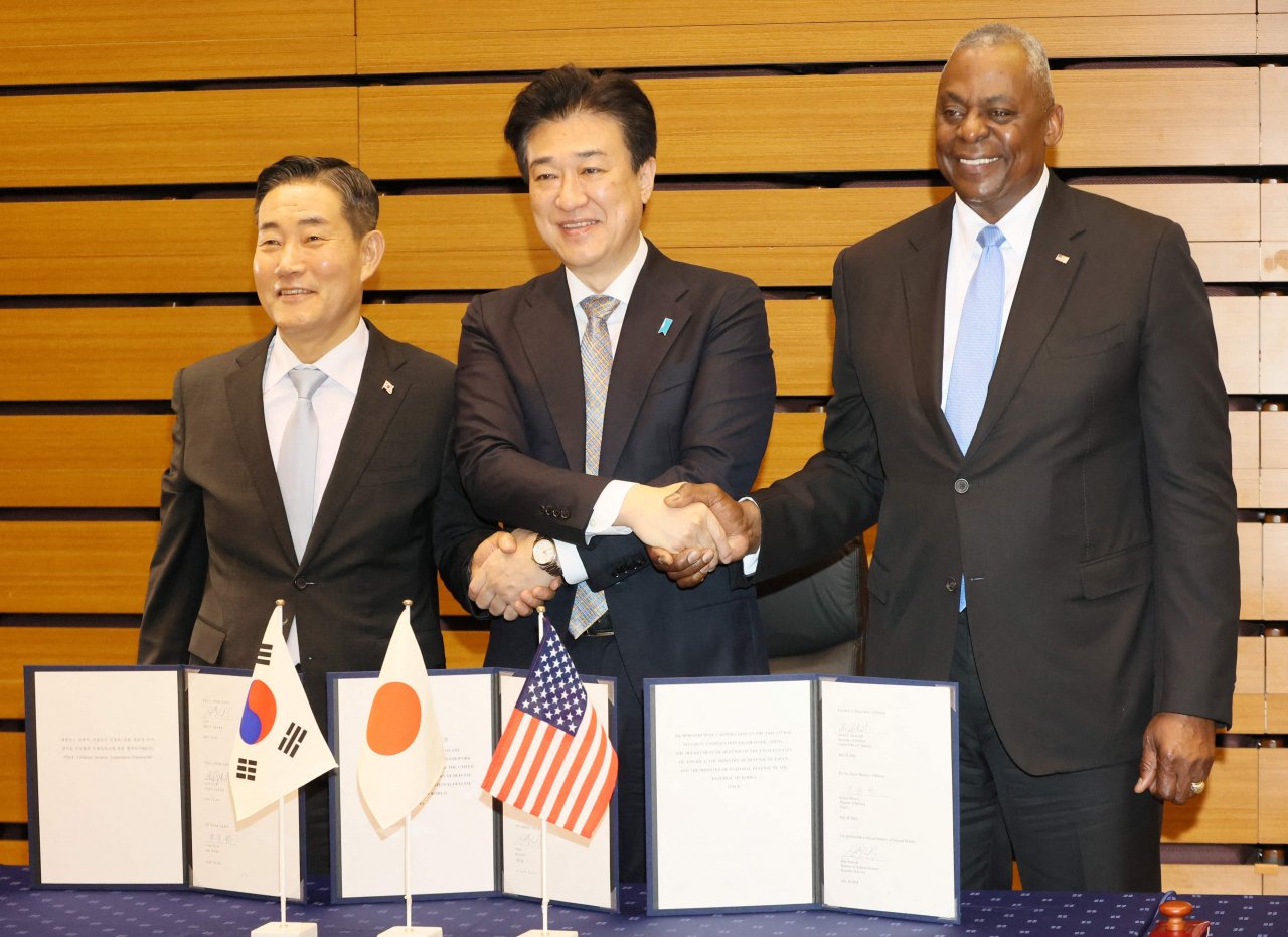 South Korean Defense Minister Shin Won-sik (left), US Secretary of Defense Lloyd Austin (right) and Japanese Defense Minister Minoru Kihara and shake hands as they exchange signed documents of their agreement of their partnership after a Japan-US-South Korea trilateral defense ministers meeting at Japan's defense ministry in Tokyo on Sunday.(Pool via AFP)