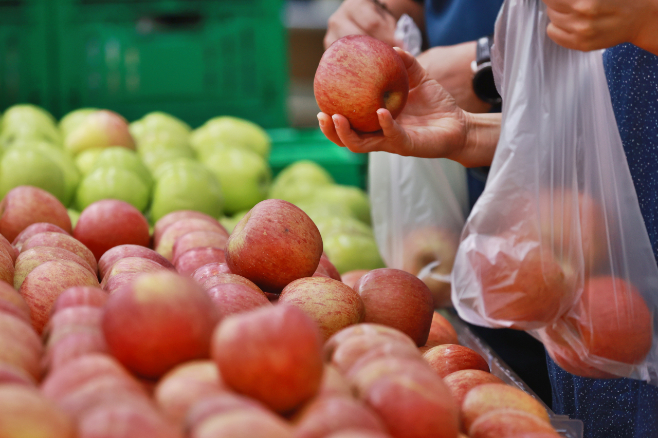 Shoppers bag apples at a supermarket in Seoul on Sunday. (Yonhap)