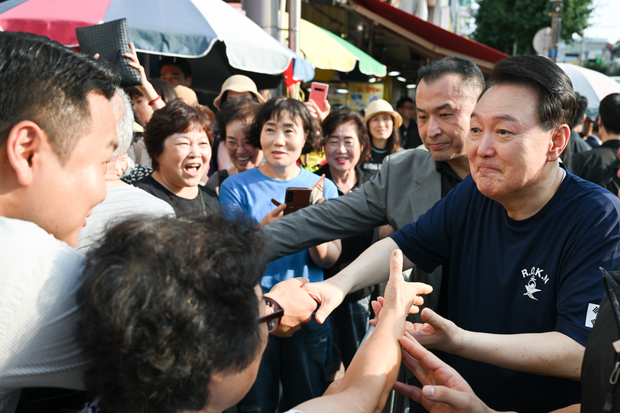 President Yoon Suk Yeol greeted by people at a local market in Tongyeong, South Gyeongsang Province, on Monday, while traveling in the region during his summer vacation. (Yonhap)