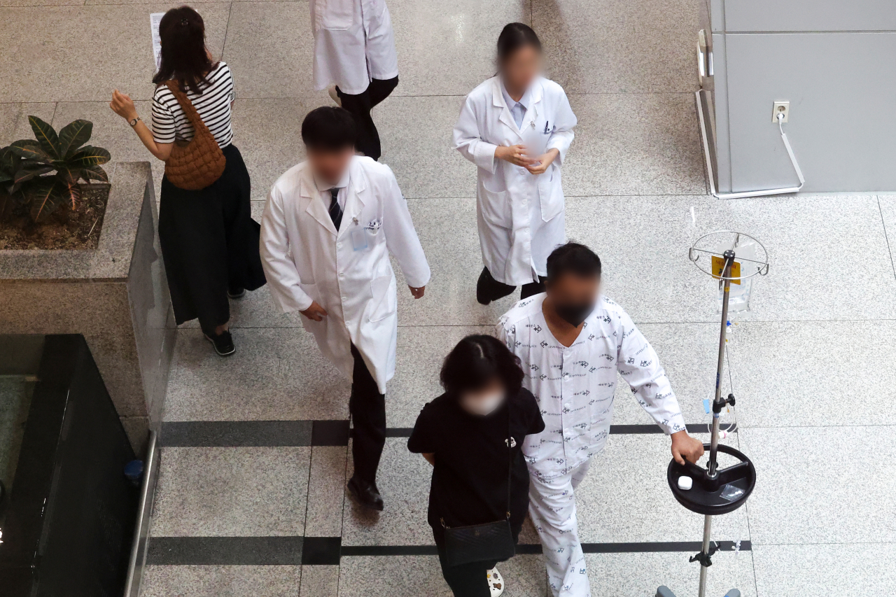 As resident doctors continue to refuse returning to work in protest of medical school quota increases, medical staff and patients are seen moving through a major hospital in Seoul on Aug. 6. (Yonhap)