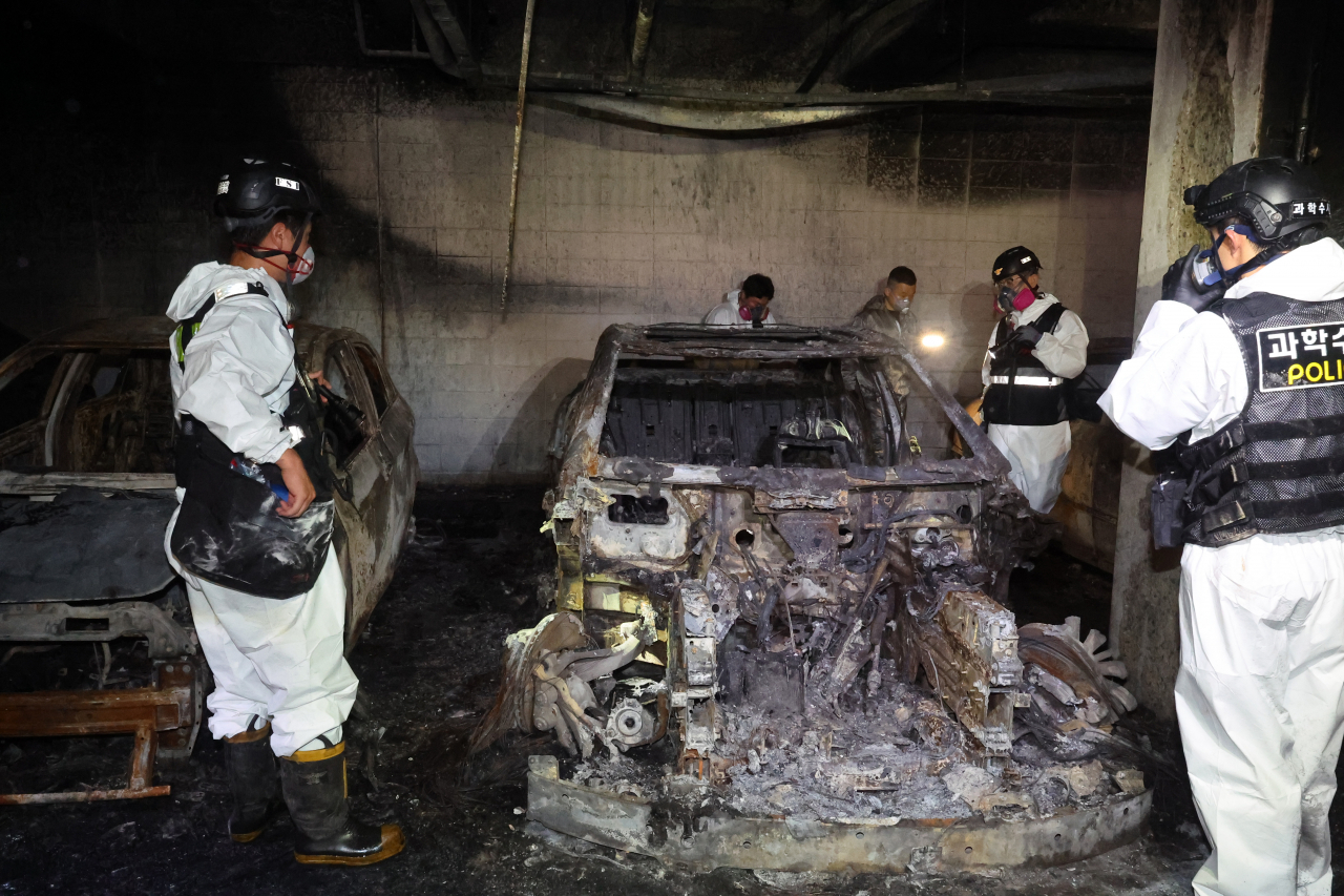 Police and fire officials conduct a joint investigation at the scene of a fire in the underground parking lot of a Cheongna apartment building in western Incheon on the morning of Aug. 2. (Yonhap)