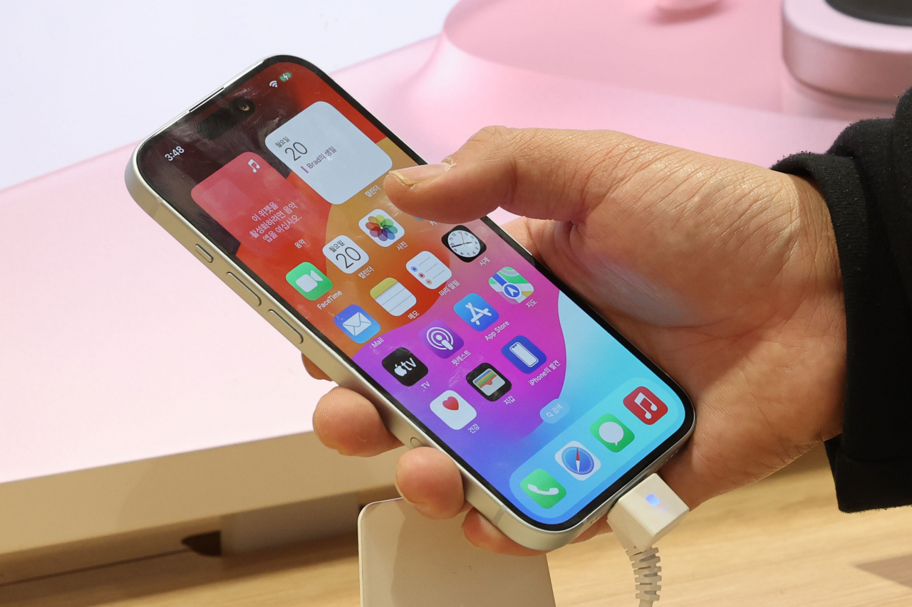 A customer tries out an iPhone 15 on display at an Apple store in Seoul. (Newsis)