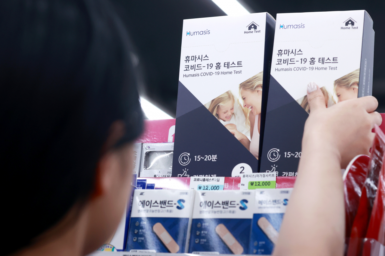 A customer picks up a COVID-19 home test kit at a convenience store in Seoul on Aug. 7. (Yonhap)