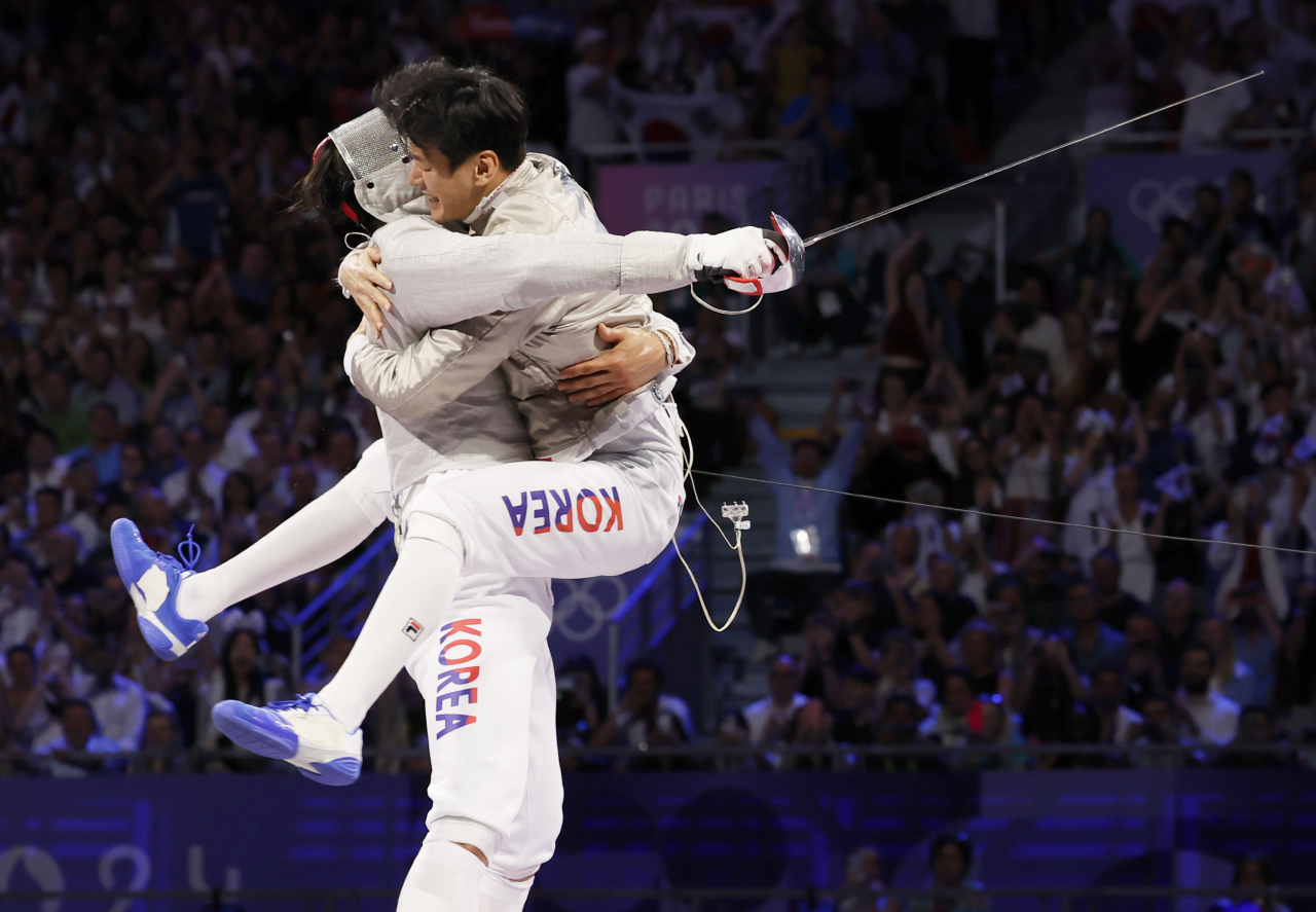 Oh Sang-wook (left) and Gu Bon-gil celebrate after winning the gold medal in the men's team saber fencing final against Hungary at the Grand Palais in Paris, France, during the 2024 Paris Olympics on Aug. 1 (Yonhap)