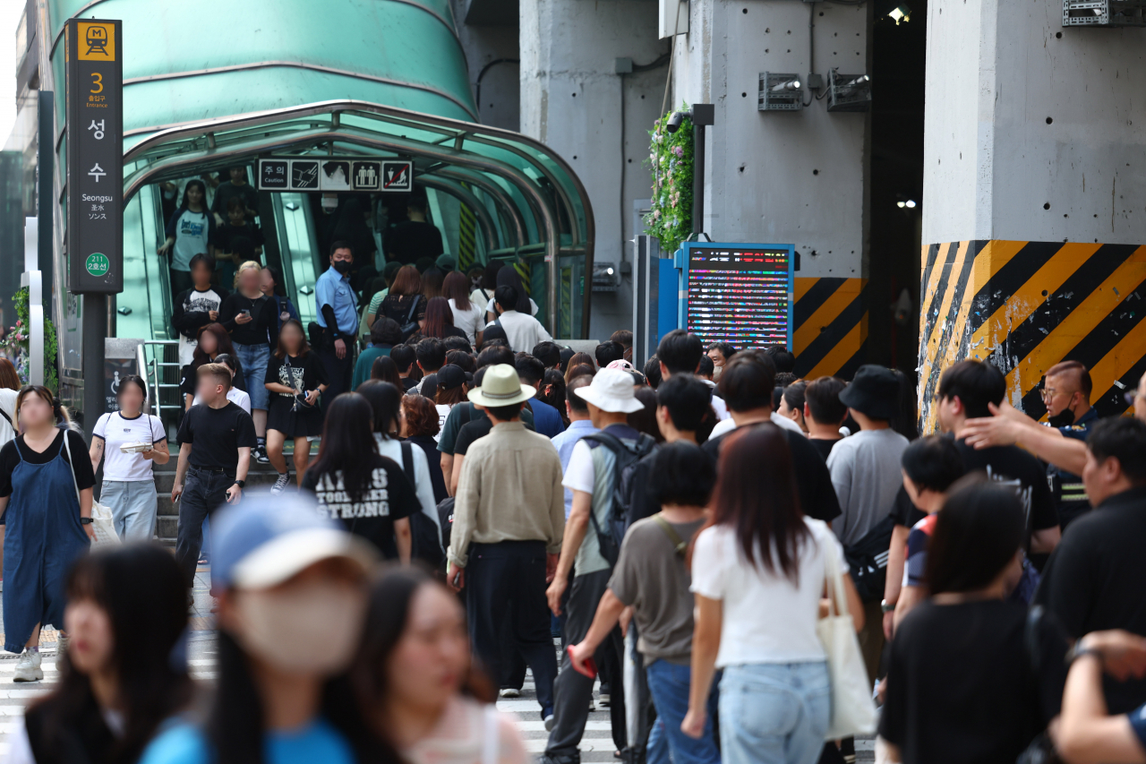 A large crowd of visitors moves in and out of Exit No. 3 at Seongsu Station on Subway Line No. 2. (Newsis)