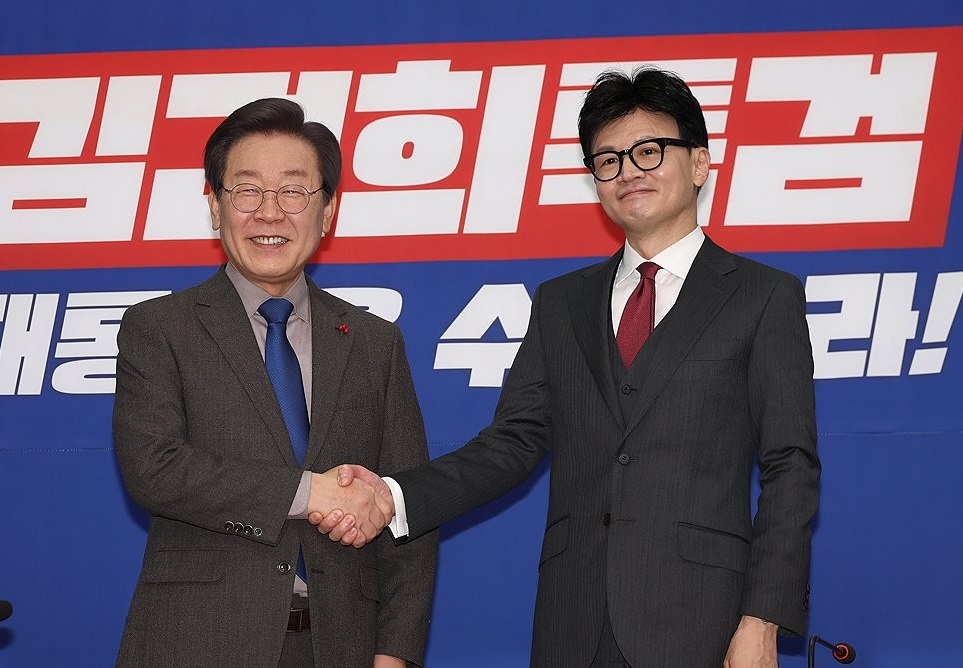 Democratic Party of Korea Chair Lee Jae-myung shakes hands with People Power Party Chair Han Dong-hoon in December 2023. (Yonhap)