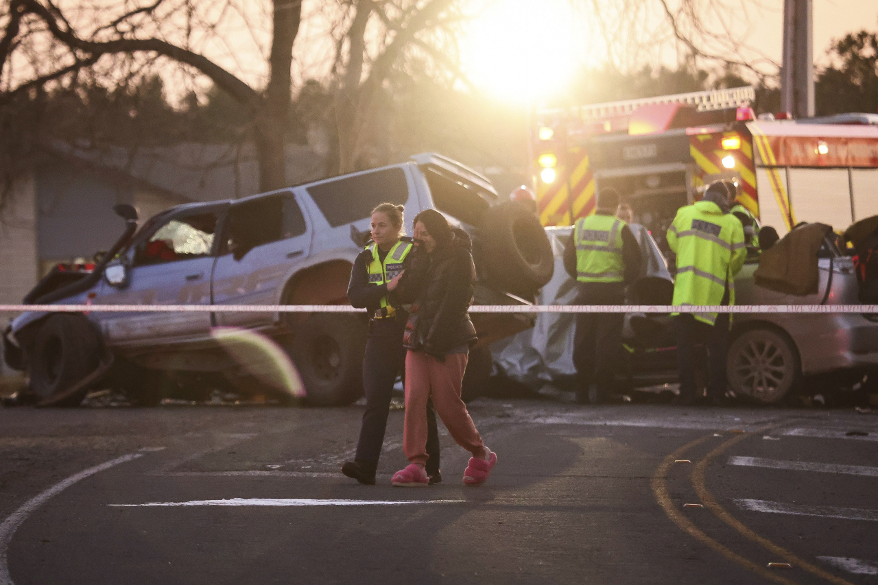 A police officer comforts a woman at a crash site near Geraldine, New Zealand, where South Korean skiers are involved in a fatal accident, Thursday. (AP)