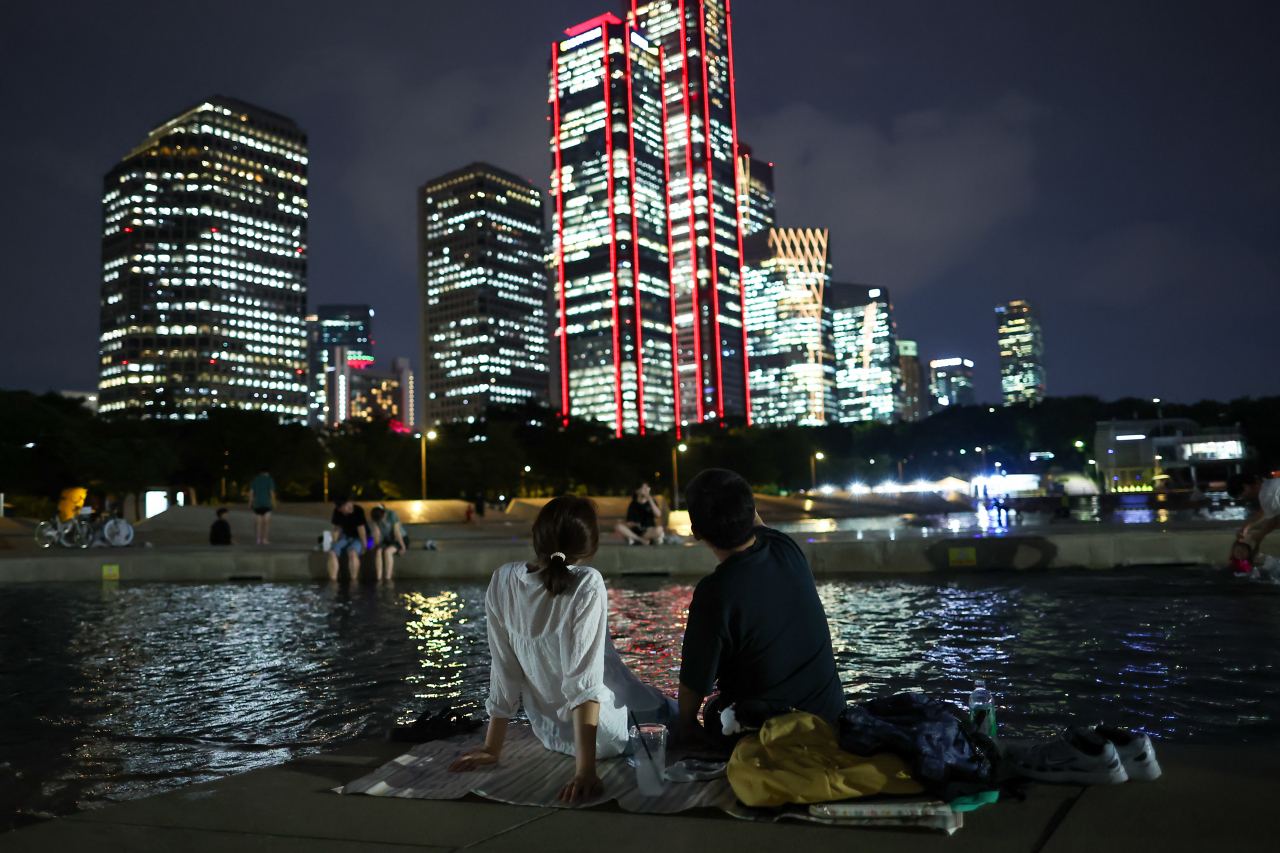 People sit on a mat at a park in Yeouido, central Seoul on Tuesday. (Yonhap)