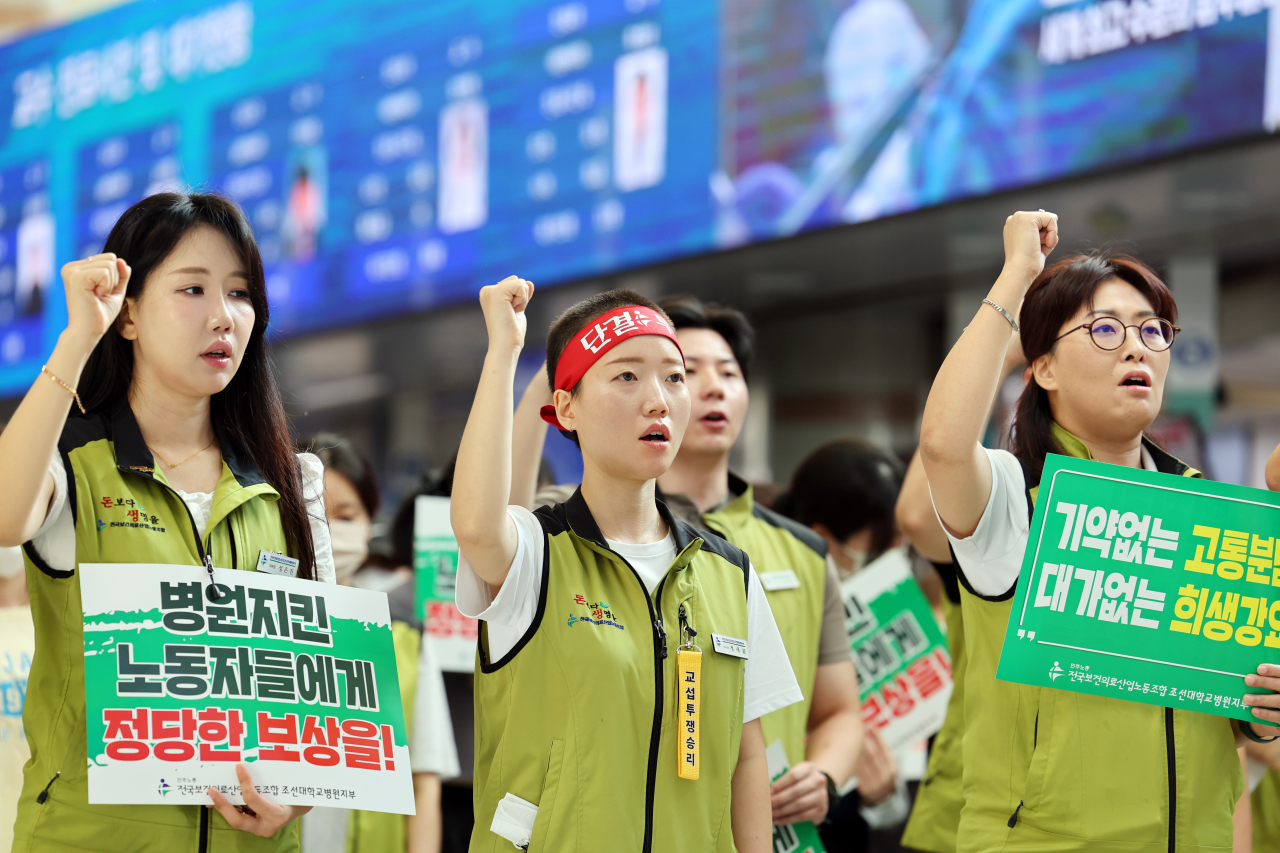 Health care workers at Chosun University Hospital hold signs and chant slogans at the hospital's lobby on Thursday,<strong></strong> signaling the start of their strike. (Yonhap)