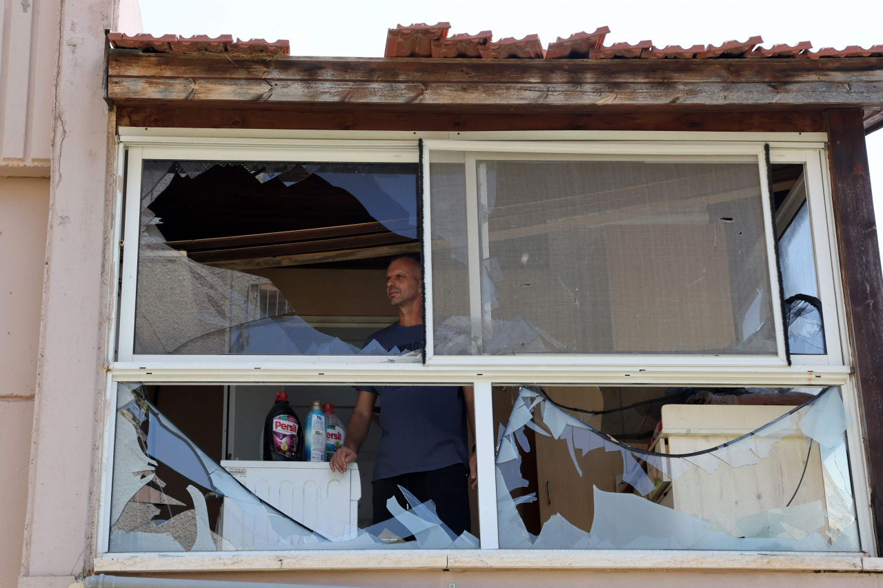 A resident checks the damage caused by a rocket fired from Lebanon in the Israeli coastal town of Acre on Aug. 25. (AFP)