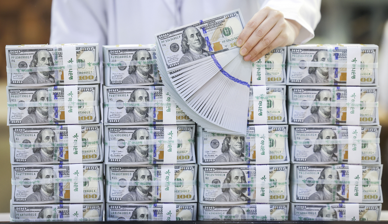 A banker checks dollars at KEB Hana Bank's Counterfeit Notes Response Center in Seoul in this file photo taken June 5. (Newsis)