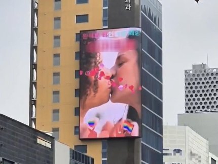 This undated photo, provided by a reader, shows a digital advertisement with same-sex couples kissing each other. (Yonhap)