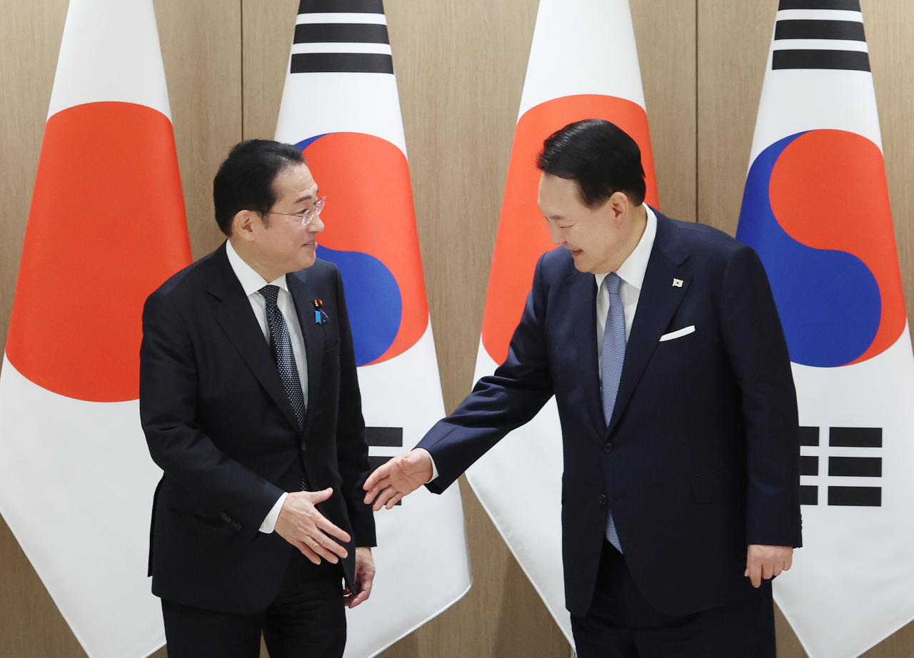 President Yoon Suk Yeol reaches a hand out to Japanese Prime Minister Fumio Kishida during a summit held at the presidential office in Yongsan, Seoul, Friday. (Joint Press Corps)