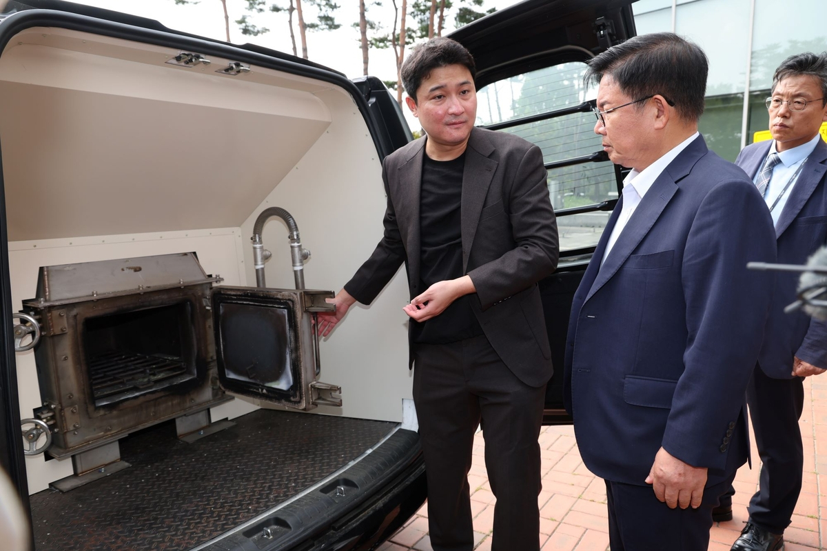 Park Gang-su (right), head of the Mapo-gu Office, listens to an explanation about the smokeless and odorless portable crematorium installed in a vehicle. (Mapo-gu Office)