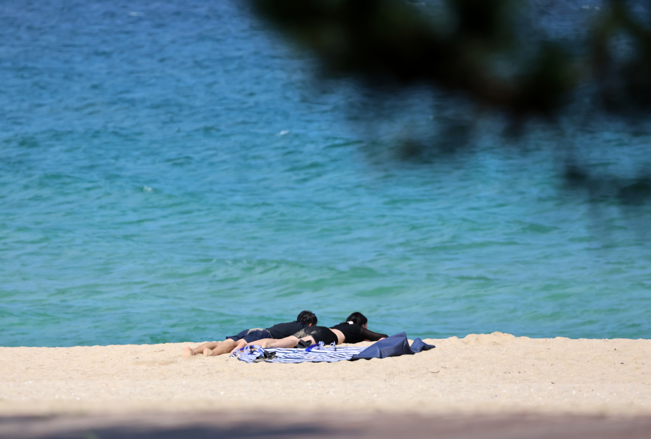 Visitors at Gyeongpo Beach in Gangneung, Gangwon Province sunbathe as daytime temperatures reached as high as 34 degrees Celsius on Tuesday. (Yonhap)