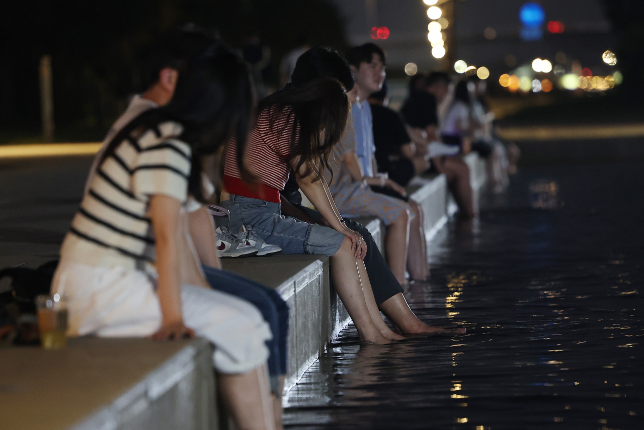 People in Seoul cool off by dipping their feet in water at Yeouido Hangang Park in Yeongdeungpo-gu, Seoul on Tuesday. (Yonhap)