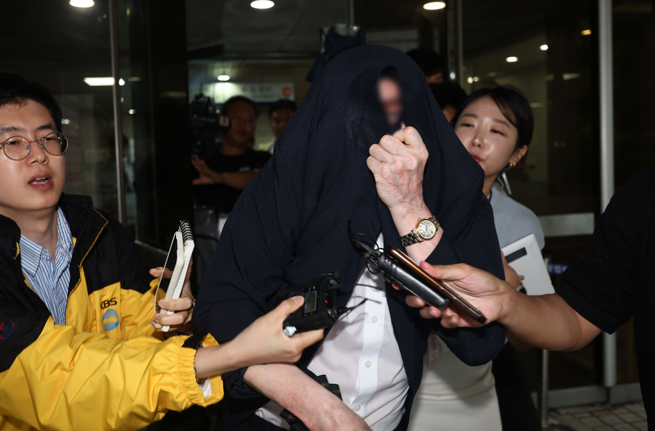 A man surnamed Son (center, front) on Thursday walks out of the courtroom after an appeals court verdict over his alleged aiding and abetting of a pump-and-dump scheme on South Korea's stock market in early 2010s. (Yonhap)