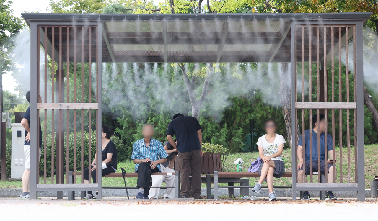 Visitors of Yeouido Park in Yeongdeungpo-gu, western Seoul, sit under a cooling fog as daytime temperatures reached as high as 34 degrees Celsius on Wednesday. (Yonhap)