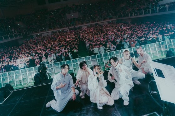 Japanese duo Yoasobi and session musicians pose for a photo during the duo's first standalone concert in Korea held at Korea University’s Hwajung Gymnasium in Seoul, Dec. 17, 2023. (LIVET)