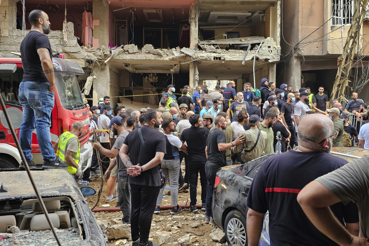 Residents look on as rescuers arrive at the scene of an Israeli missile strike in the southern suburbs of Beirut, Friday. (AP)