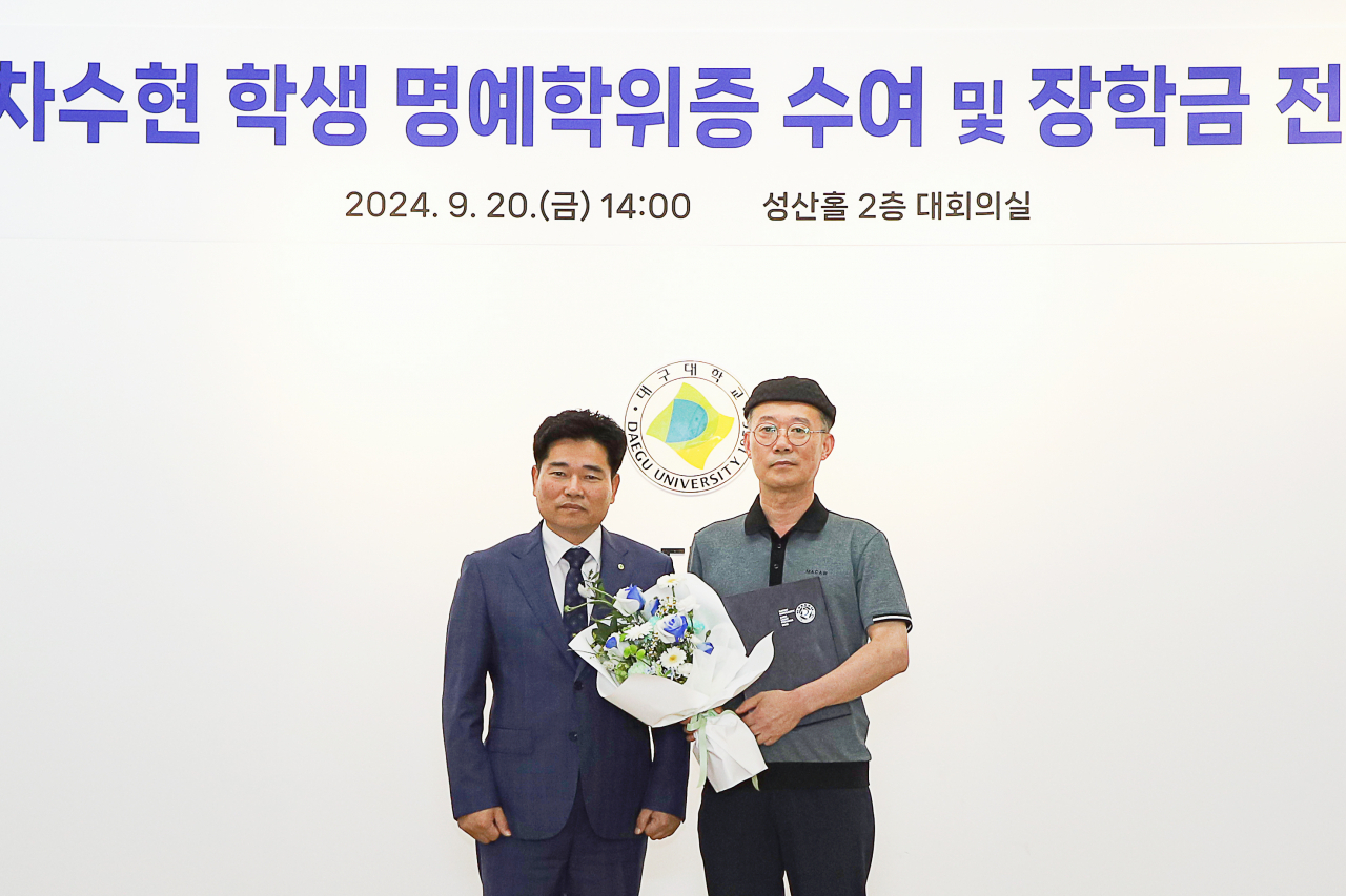 Cha Min-su (right), the father of late Cha Su-hyeon, poses with Daegu University President Park Soon-jin after receiving an honorary degree on behalf of his daughter on Friday. (Daegu University)