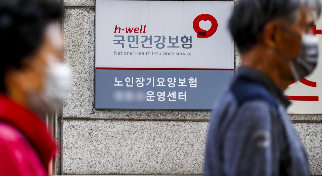 Two pedestrians pass by the National Health Insurance Service building in Seoul. (The Korea Herald DB)