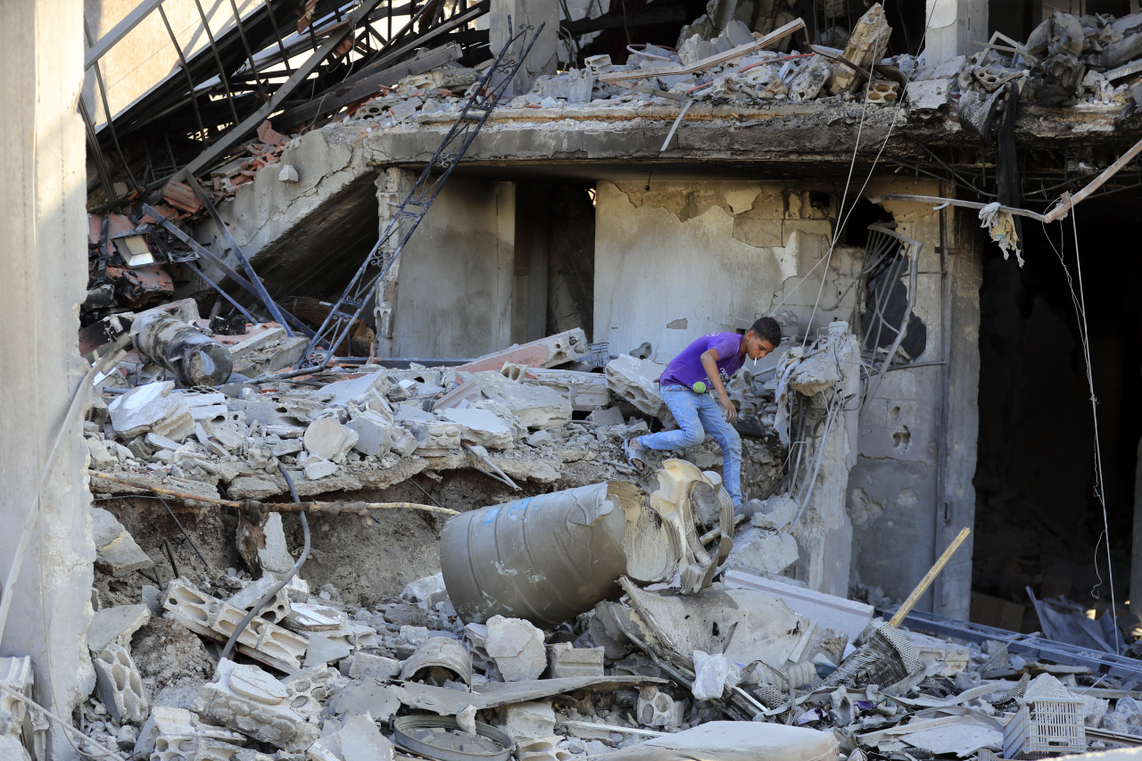 A boy checks the damage to a building hit in an Israeli airstrike in the southern village of Akbieh, Lebanon, Tuesday. (AP-Yonhap)