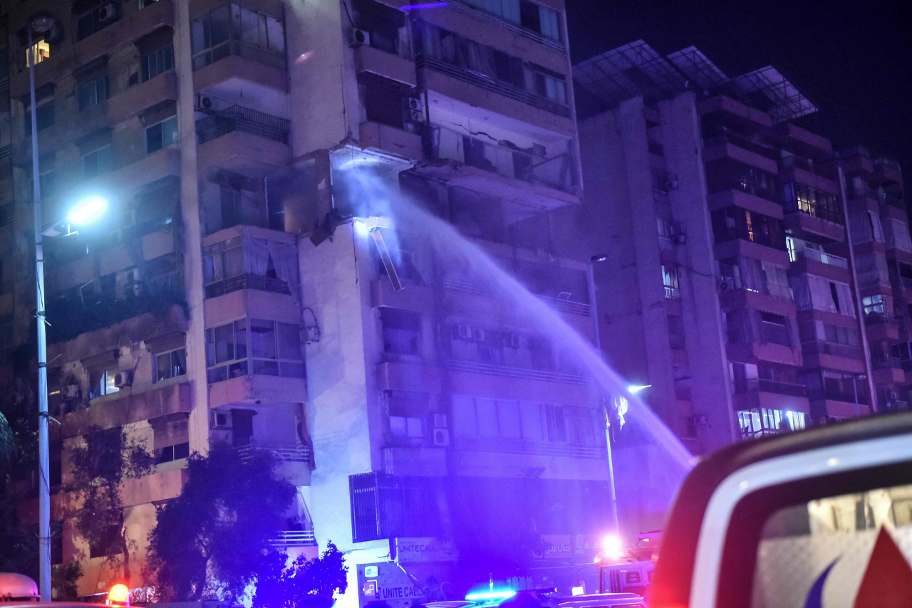 Firefighters douse the flames of an apartment building hit by an Israeli air strike in Beirut's Cola district, Monday. (AFP)