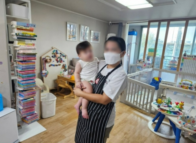 A Filipino caregiver takes care of an infant in a home in Seoul. (The Seoul Metropolitan Government)