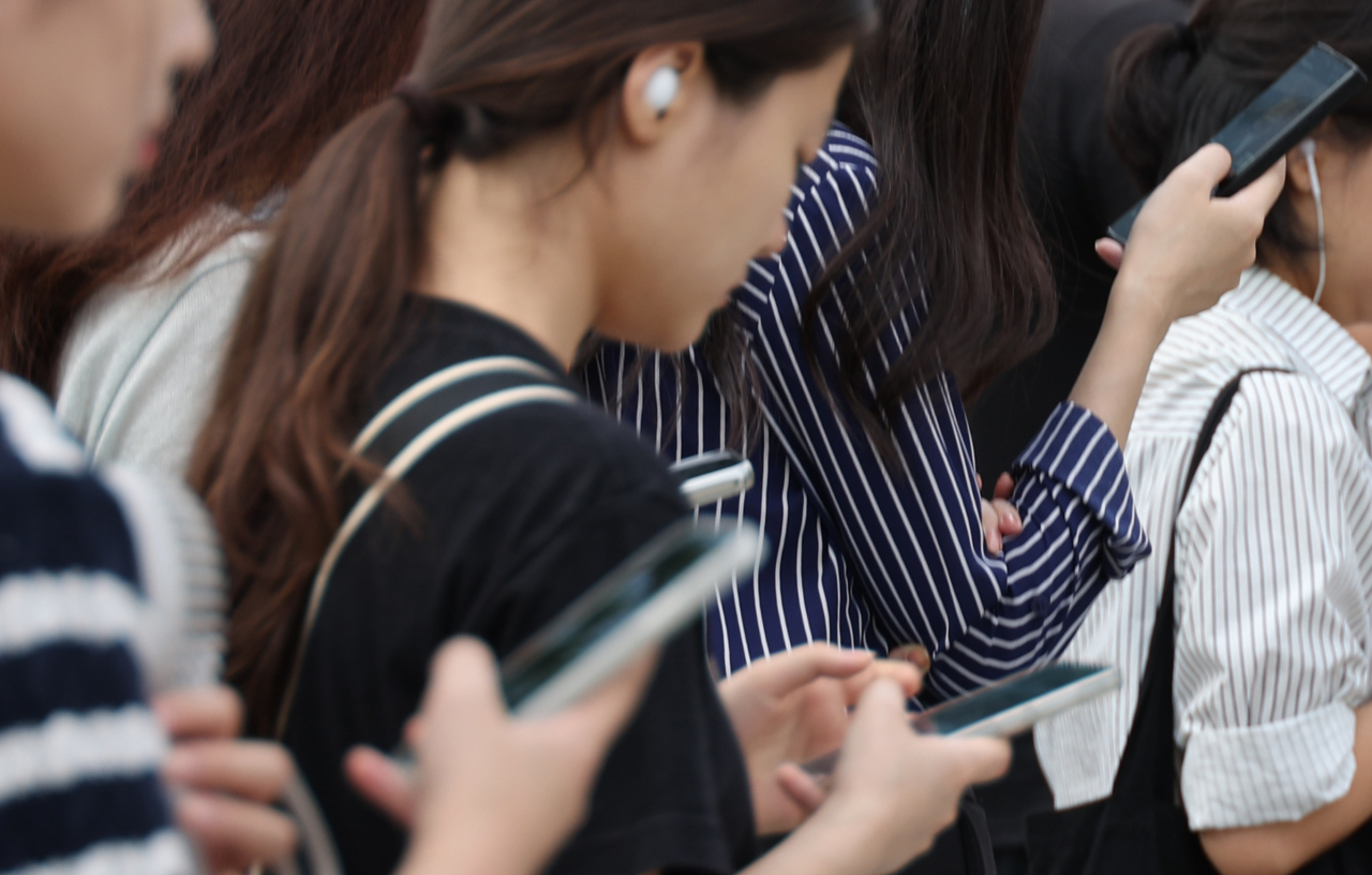 People use their smartphones while commuting in Seoul, Sept. 19. (Yonhap)