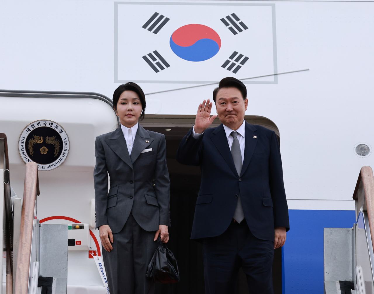 President Yoon Suk Yeol (right) waves hands before boarding Air Force One with first lady Kim Keon Hee at Seoul Air Base in Seongnam, Gyeonggi Province, Sunday. Yonhap