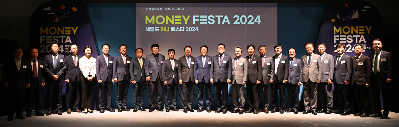 Business leaders from financial sectors pose for a photo during the opening ceremony of the Money Festa 2024 conference at Coex in southern Seoul on Oct. 1. From left are Jeong Kyu-hwang, vice president at Woori Financial Group; Lee Ki-heon, vice chairman of Korea Listed Companies Association; Cho Jae-bak, senior vice president at Naver Pay; Lee Chang-hwa, vice president at Korea Financial Investment Association; Lee Eun-mi, president of Toss Bank; Kim Jae-sik, vice chairman of Korea Housing Association; Kim Kyu-cheol, director at Land Ministry, director of Housing and Land Office at Land Ministry; Jang Yeon-soo, vice president of KB Kookmin Bank; Koscom President Yoon Chang-hyun; Kim Chul-ju, chairman of Korea Life Insurance Association; Cho Yong-byoung, chairman of Korea Federation of Banks; Herald Media Group CEO Choi Jin-young; Kim Byoung-hwan, chairman of Financial Services Commission; Jin Ok-dong, chairman of Shinhan Financial Group; Lee Byung-rhae, chairman of General Insurance Association of Korea; Heo Chang-eon, chairman of Korea Insurance Development Institute; Tak Yoon-seong, vice president of Kbank; Ha Keun-cheol, vice president at BNK Financial Group; Kang Seog-hoon, chairman of KDB Bank; Oh Hwa-kyung, chairman of Korea Federation of Savings Banks; Moon Hyung-wook, director at Korea Deposit Insurance Corporation; Lee Byung-hoon, vice chairman of Korea Housing Builders Association; and Kim Young-hoon, vice president of Hana Bank. (Lee Sang-sub/The Korea Herald)