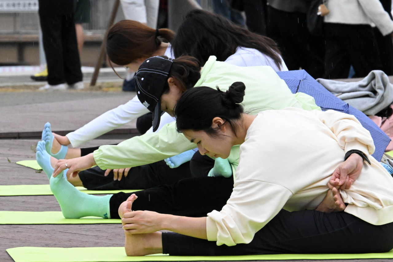 Participants join in an outdoor yoga session with activewear brand Mulawear on the south end of Banpo Bridge during Wellness Seoul 2024 on Sunday. (Im Se-jun/The Korea Herald)