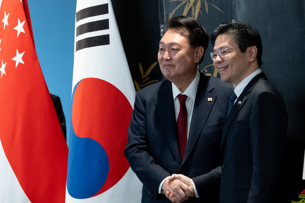 President Yoon Suk Yeol (left) shakes hands with Singaporean Prime Minister Lawrence Wong after a joint press conference on Tuesday at the Parliament House of Singapore. (Pool photo via Yonhap)