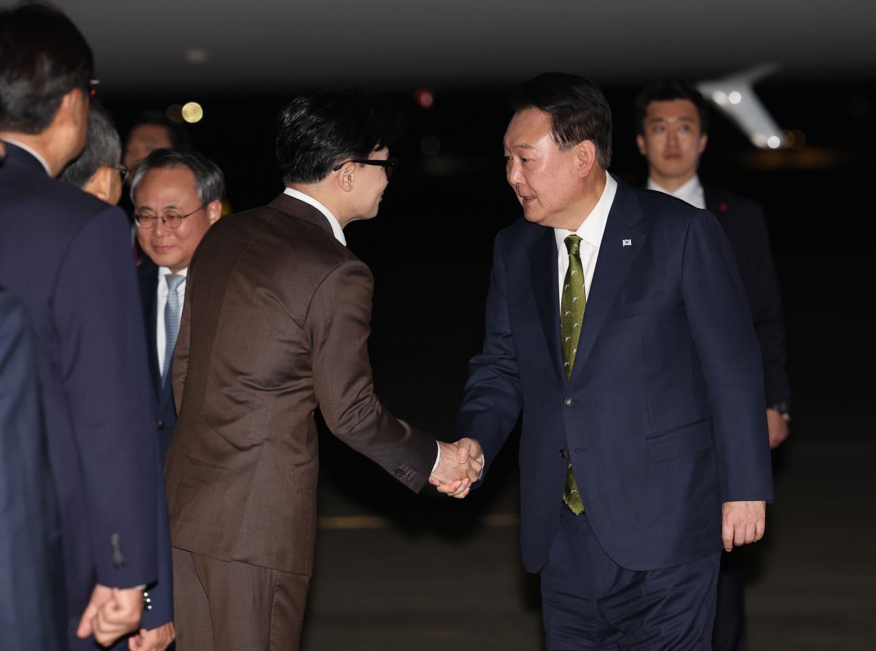 President Yoon Suk Yeol (right) shakes hands with People Power Party leader Han Dong-hoon upon arriving at Seoul Air Base, just south of Seoul, on Friday, following a three-nation tour of Southeast Asia. (Yonhap)