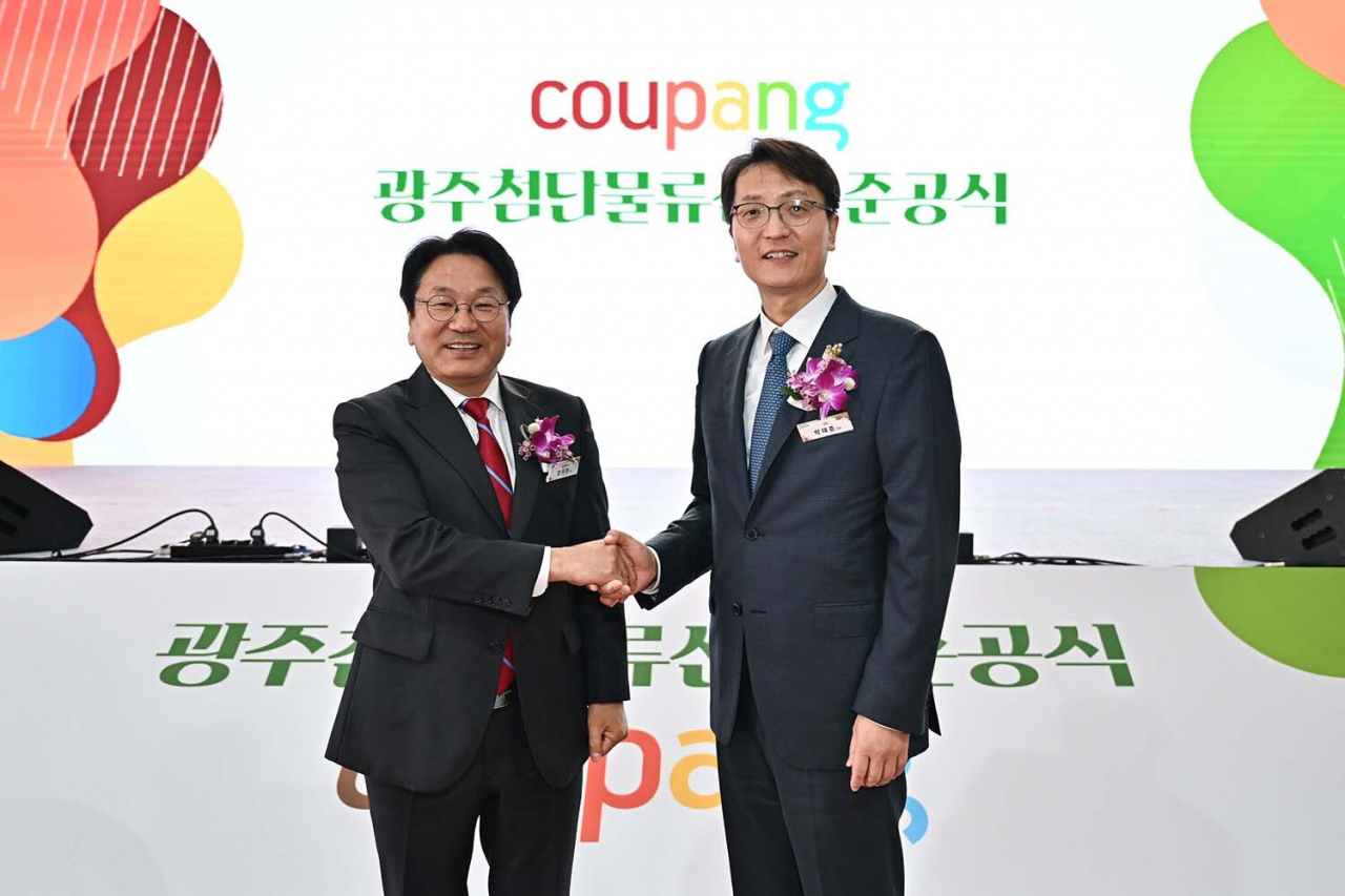 Gwangju Mayor Kang Gi-jung (left) and Coupang Representative Director Park Dae-jun shake hands at the completion ceremony for Coupang's Gwangju fulfillment center on Monday. (Coupang)