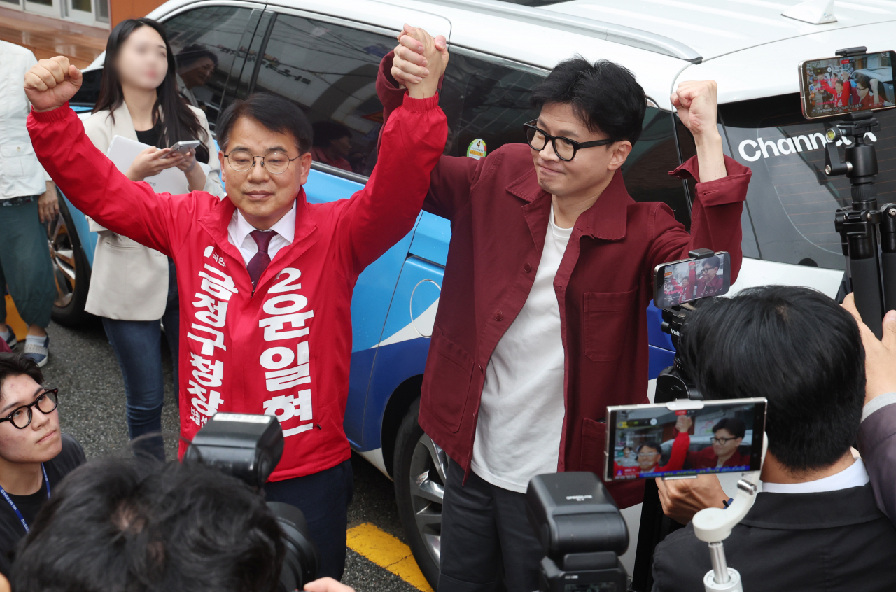 People Power Party Chair Han Dong-hoon, right, holds hands with Yoon Il-hyun, the conservative party candidate for the mayor of Geumjeong district in Wednesday's by-elections in Busan on Tuesday. (Yonhap)