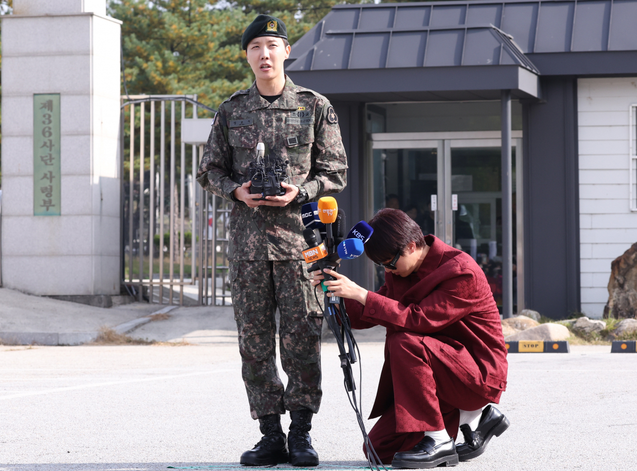 Jin kneels down and holds microphones for J-Hope in front of the 36th Recruit Training Battalion in Wonju, Gangwon Province, Thursday. (Yonhap)